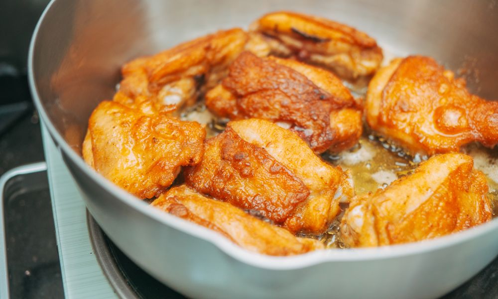 Muslos de pollo cocinándose en una sartén