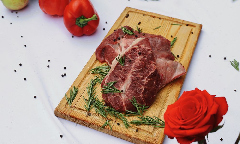 Carne de res cruda acompañada de vegetales sobre tabla